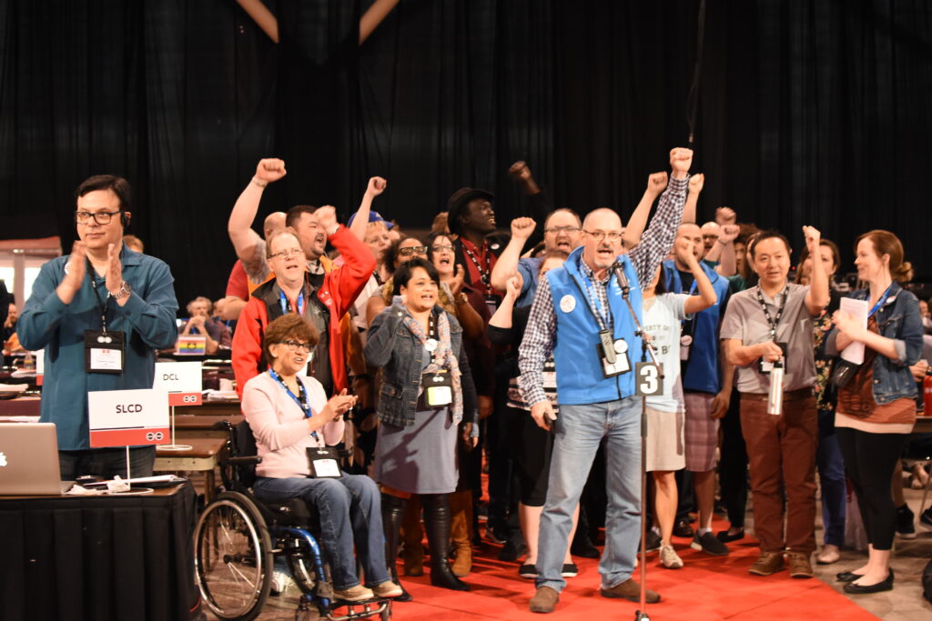 Group of people on stage with their fists raised.